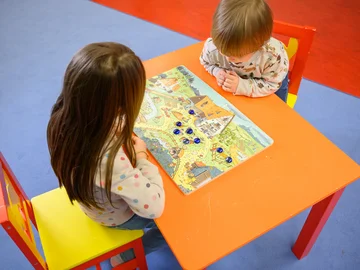 Zwei Kinder am Tisch über einem mathematischen Brettspiel.