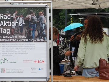 Drei junge Frauen reparieren ein Fahrrad, im Vordergrund ein Plakat des Rad-Aktions-Tags