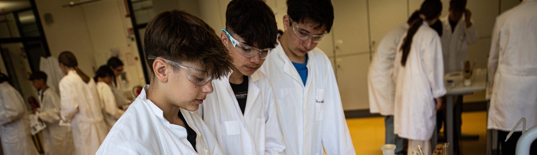 Drei Schüler mit Schutzbrillen bei einem chemischen Experiment