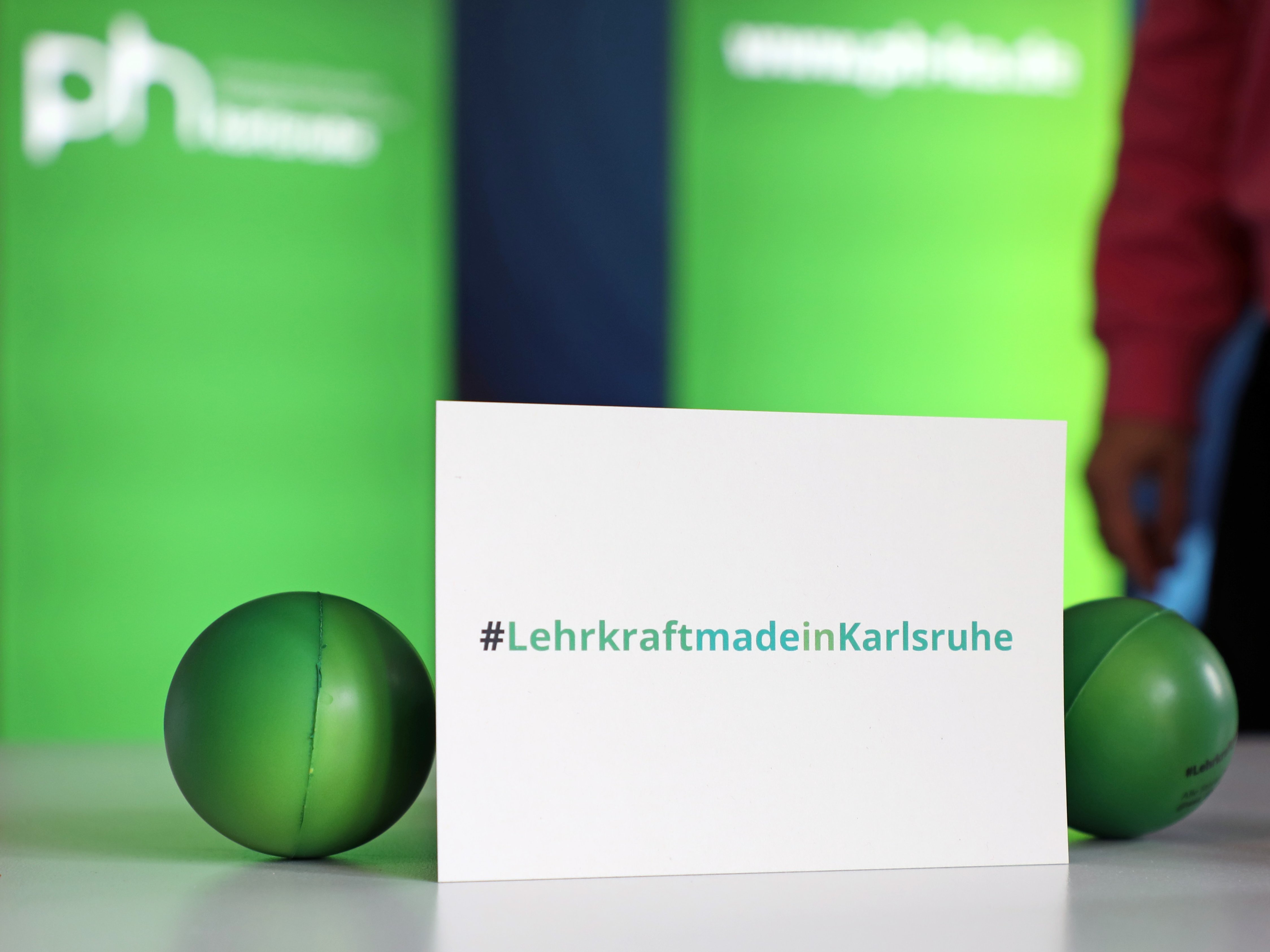 Eine Postkarte lehnt auf einer Tischplatte mit dem Aufdruck hashtag LehrkraftmadeinKarlsruhe