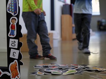 KiTa-Kind steht im Gang, auf dem Boden liegen Spielkarten