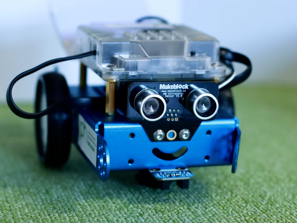 ein kleiner fahrbarer Roboter steht auf einem Teppich im LLL Informatik