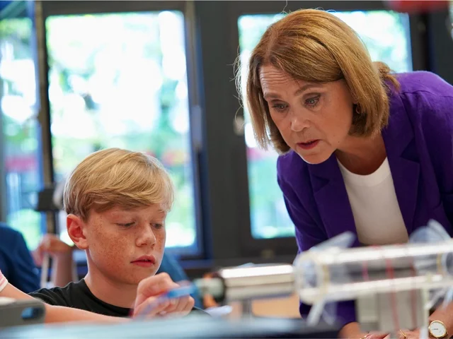 Die Ministerin schaut einem Schüler beim Experimentieren über die Schulter.