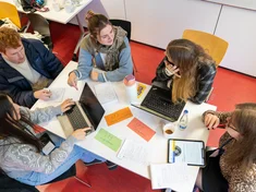 Eine Gruppe von Studierenden arbeitet gemeinsam an einem Tisch.