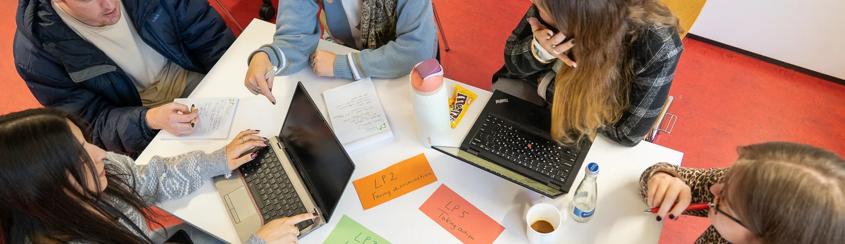A group of students working together sitting on a table.