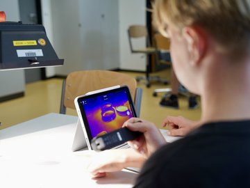 Zwei Schüler in einem Labor schauen auf einen Tablet-Bildschirm.