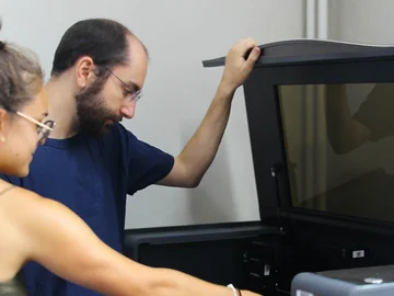 Zwei Personen bedienen einen Lasercutter.