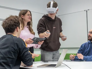 Eine Gruppe aus vier jungen Wissenschaftler:innen experimentiert mit einer VR Brille
