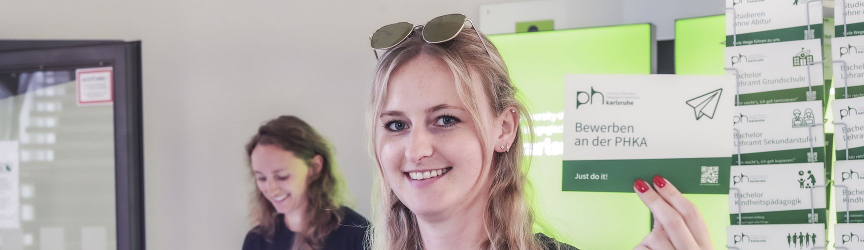Eine Mitarbeiterin des SSZ hält eine Postkarte zum Thema Bewerben in die Höhe