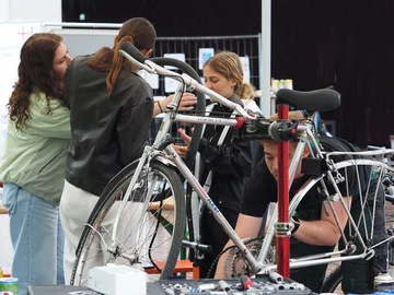 Drei junge Menschen reparieren Fahrräder