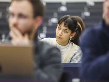Eine Studentin folgt in einem Hörsaal einem Vortrag.