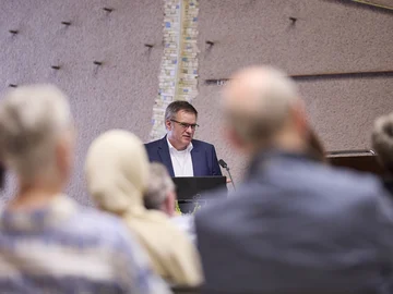 Durch Publikumsköpfe von hinten nindurch ist Prof. Gleser bei seinem Vortrag im Bürgersaal bei PHKA im Rathaus zu sehen.