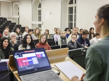 In einem Hörsaal hören Menschen einer Präsentation zu.