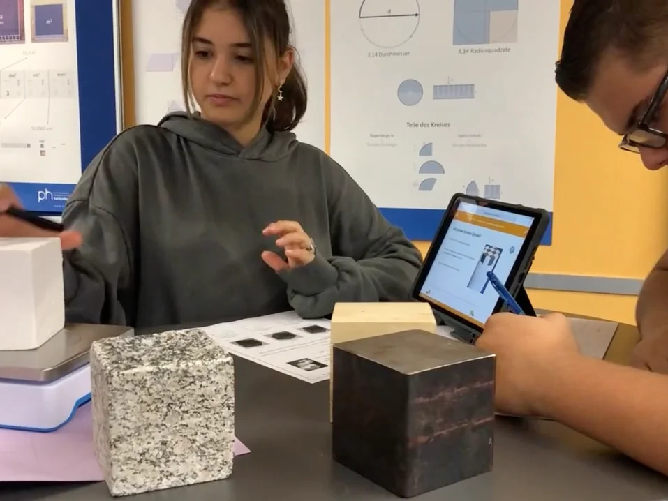 eine Schülerin und ein Schüler beschäftigen sich im Lernbüro Mathematik des Projekts ProNaMU selbstständig mit den verschiedenen haptischen, analogen und digitalen Materialien
