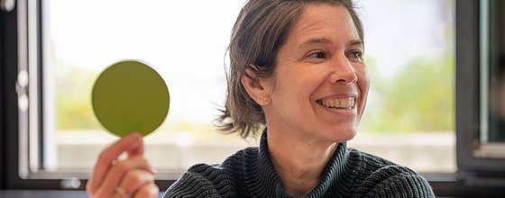 Eine Person hält einen grünen Punkt aus Papier in die Höhe.