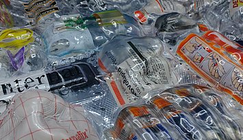 Pernilla Philip_Workshop Das Bild zeigt eine Sammlung von medizinischen Verpackungen und Einwegmaterialien, die unter einer klaren, möglicherweise kunststoffartigen oder harzartigen Oberfläche eingeschlossen sind. Zu sehen sind beispielsweise: Infusionsbeutel Blisterverpackungen Einweghandschuh-Verpackungen mit Anleitungen Teile von Spritzen oder medizinischen Geräten Verpackungsbeschriftungen in mehreren Sprachen Das Arrangement wirkt bewusst gestaltet, fast skulptural – möglicherweise handelt es sich um ein Kunstwerk oder eine kritische Auseinandersetzung mit dem Thema medizinischer Müll, Sterilität und Wegwerfgesellschaft.