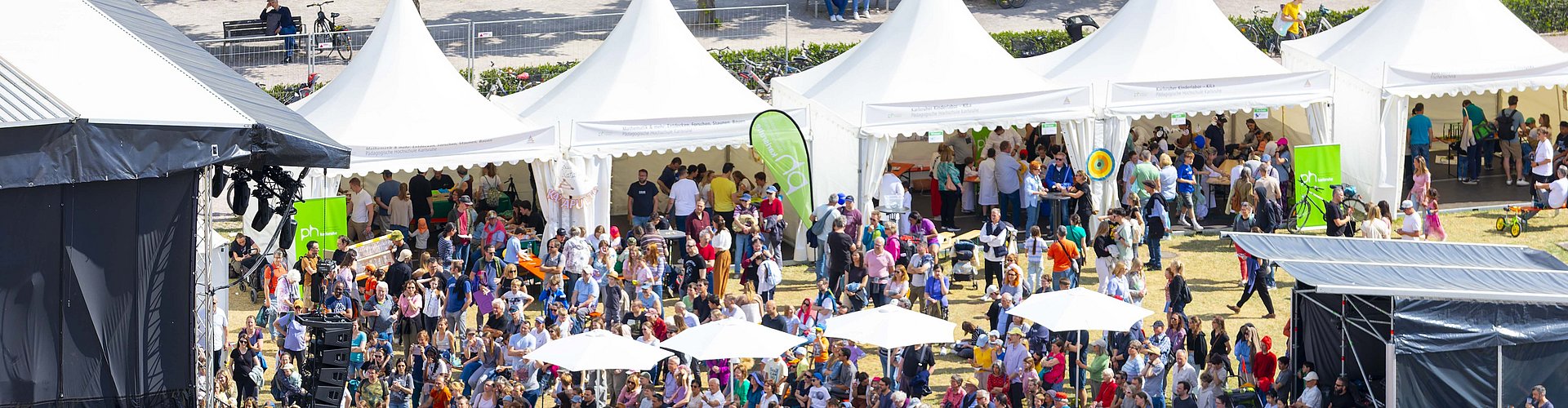 Ein Blick von oben auf das EFFEKTE Wissenschaftsfestival 2025. Zu sehen sind die von der PHKA bespielten Pagodenzelte, ein teil von der bühne und sehr viele Menschen.