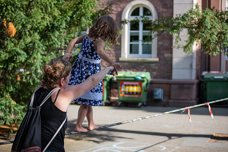 Familienfreundlicher Campus Ein Kind läuft auf auf dem PH Campus einen Seil. Es wird von einer erwachsenen Person unterstützt.