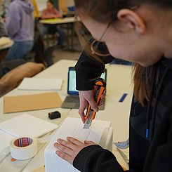 Zu sehen ist einne Schülerin, die eine Sonde baut.